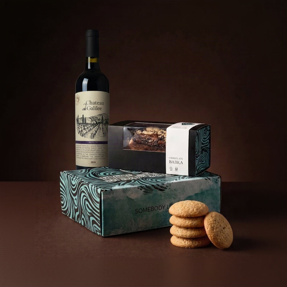 A gourmet gift set featuring a bottle of Chateau Callee red wine, a box of chocolate-covered cookies, and two patterned gift boxes from Sombody and Barba Chocolate, arranged on a dark brown background.